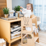 Meisje staat op houten leertoren met konijntjesprint van Fits4Kids en reikt naar aanrecht