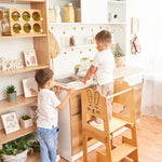 Twee kinderen staan samen bij de houten leertoren van Fits4Kids bij het aanrecht