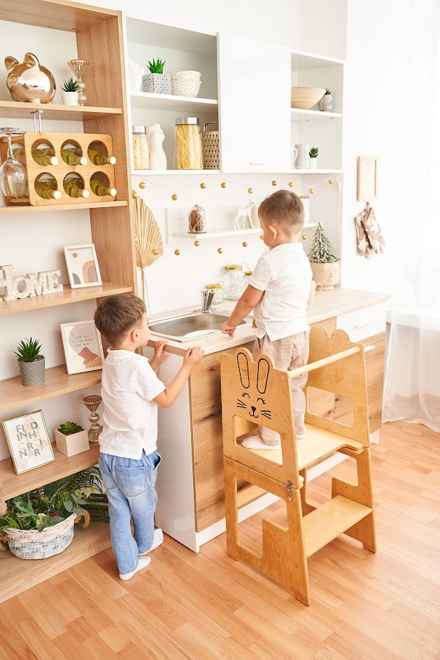 Twee kinderen staan samen bij de houten leertoren van Fits4Kids bij het aanrecht